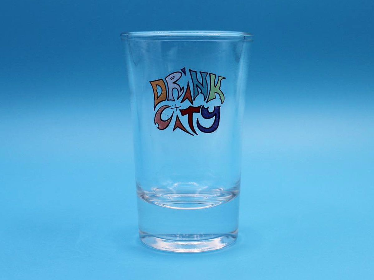 Drink City Shotglas vor blauem Hintergrund